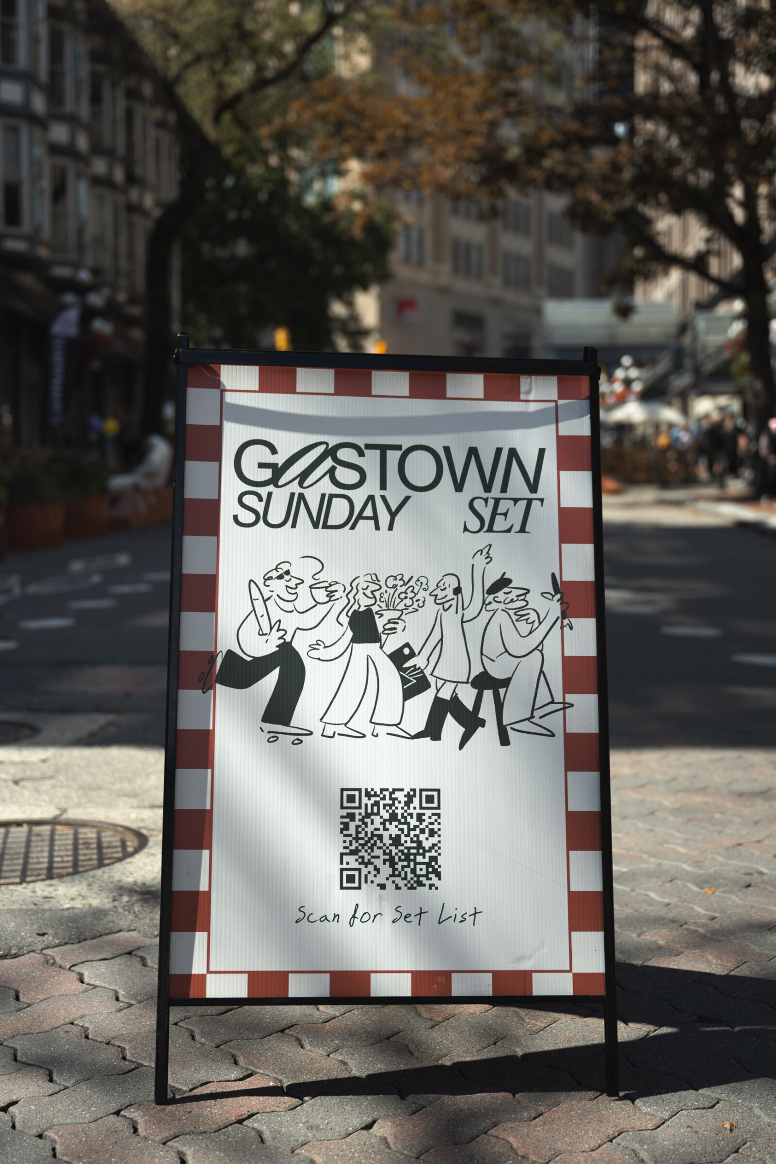 A sandwich board that reads, "Gastown Sunday Set" paired with stylized black and white illustrations of a crowd of people. There is a QR code below for information.